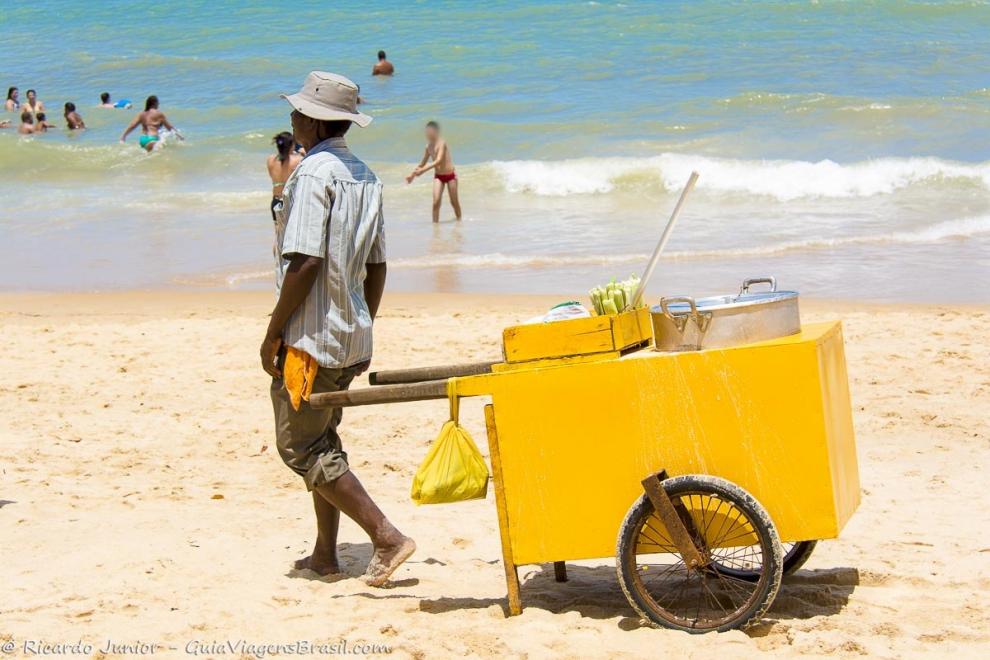 Imagem de um vendedor de milho com seu carrinho nas areias da Praia de Taperapuan.